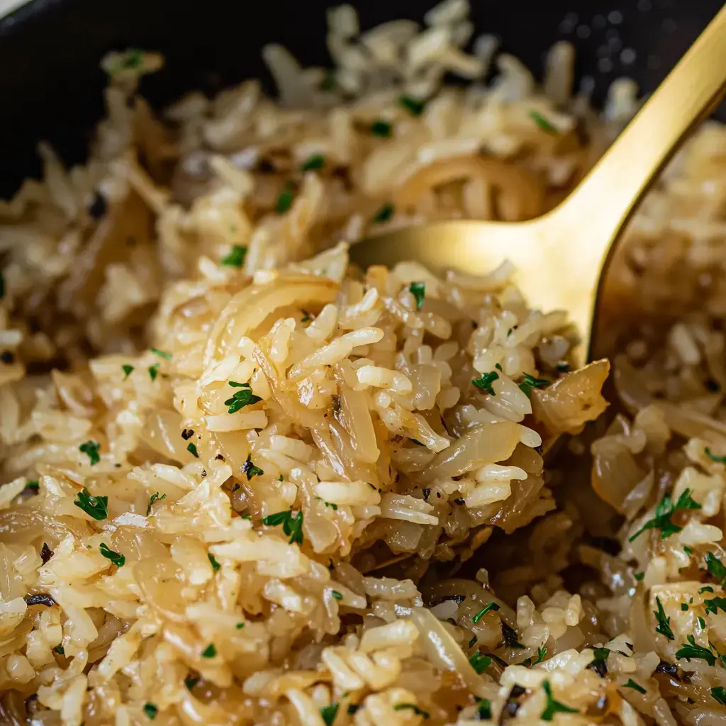 Close-up of buttery rice with onions and parsley served in a dark dish.