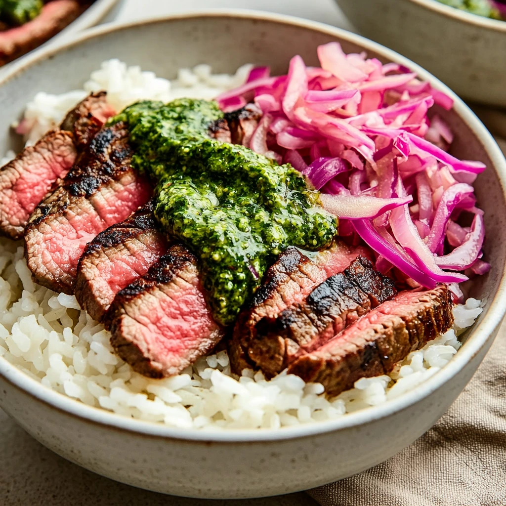 A filling bowl of rice with thin slices of steak and fresh green sauce drizzled on top.